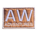 AWA Title embroidered travel patch featuring large white AW lettering above Adventures text on a tan rectangular background.