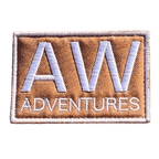 AWA Title embroidered travel patch featuring large white AW lettering above Adventures text on a tan rectangular background.
