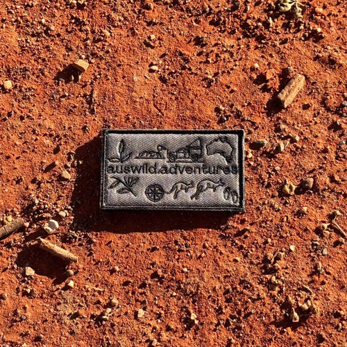 AWA Graphic embroidered travel patch featuring Aus Wild Adventures lettering surrounded by Uluru, a 4WD, kangaroos, compass, gum leaves and an Australia outline.