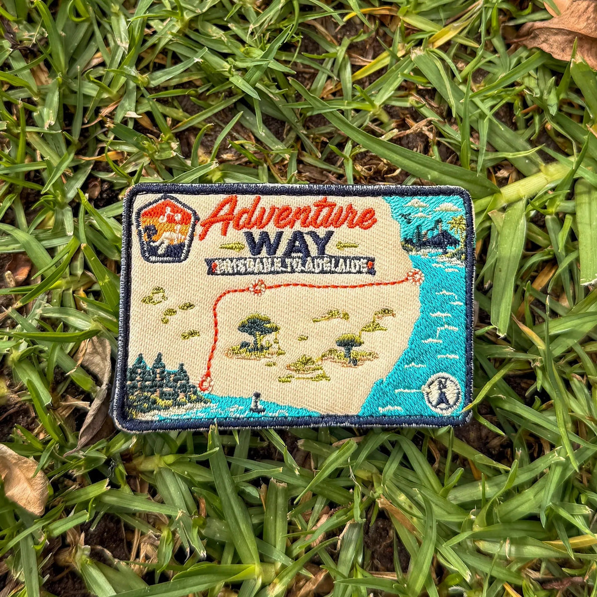 Adventure Way embroidered travel patch featuring map of the Brisbane to Adelaide route with dotted red road, coastal cities, outback trees and a compass.