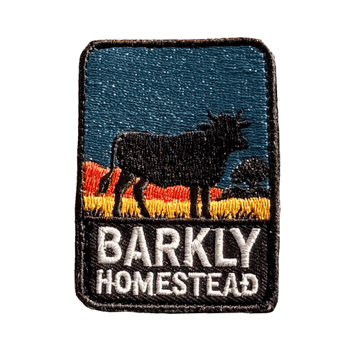 Barkly Homestead embroidered travel patch featuring dark cattle silhouette against orange outback hills and a teal sky.