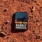 Barkly Homestead embroidered travel patch featuring dark cattle silhouette against orange outback hills and a teal sky.