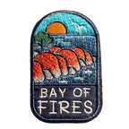 Bay of Fires embroidered travel patch featuring orange coastal boulders, turquoise ocean, a setting sun and a flying seabird.
