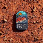 Bay of Fires embroidered travel patch featuring orange coastal boulders, turquoise ocean, a setting sun and a flying seabird.