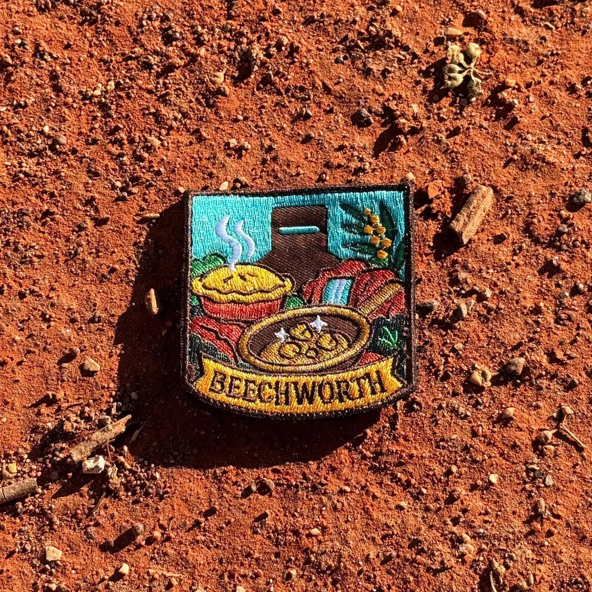 Beechworth embroidered travel patch featuring gold pan, steaming pie, historic chimney, waterfall and native wattle flowers.