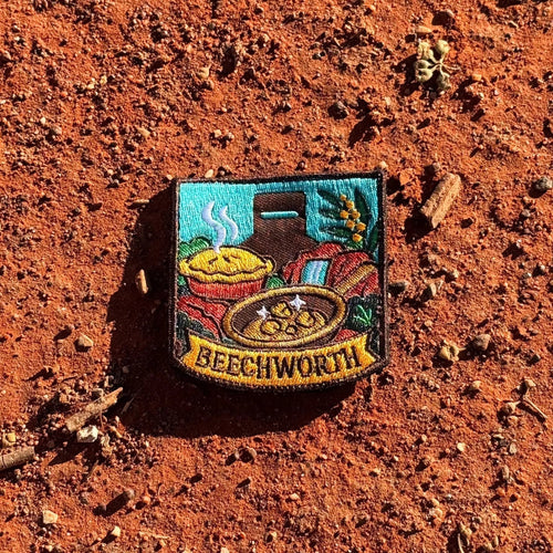 Beechworth embroidered travel patch featuring gold pan, steaming pie, historic chimney, waterfall and native wattle flowers.