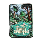 Berry Springs embroidered travel patch featuring swimmers in turquoise water beside a waterfall and lush tropical palms.