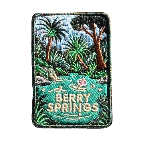 Berry Springs embroidered travel patch featuring swimmers in turquoise water beside a waterfall and lush tropical palms.