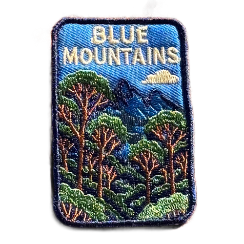 Blue Mountains embroidered travel patch featuring eucalyptus forest, layered blue mountain peaks and a white cloud against a deep blue sky.