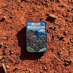 Blue Mountains embroidered travel patch featuring eucalyptus forest, layered blue mountain peaks and a white cloud against a deep blue sky.