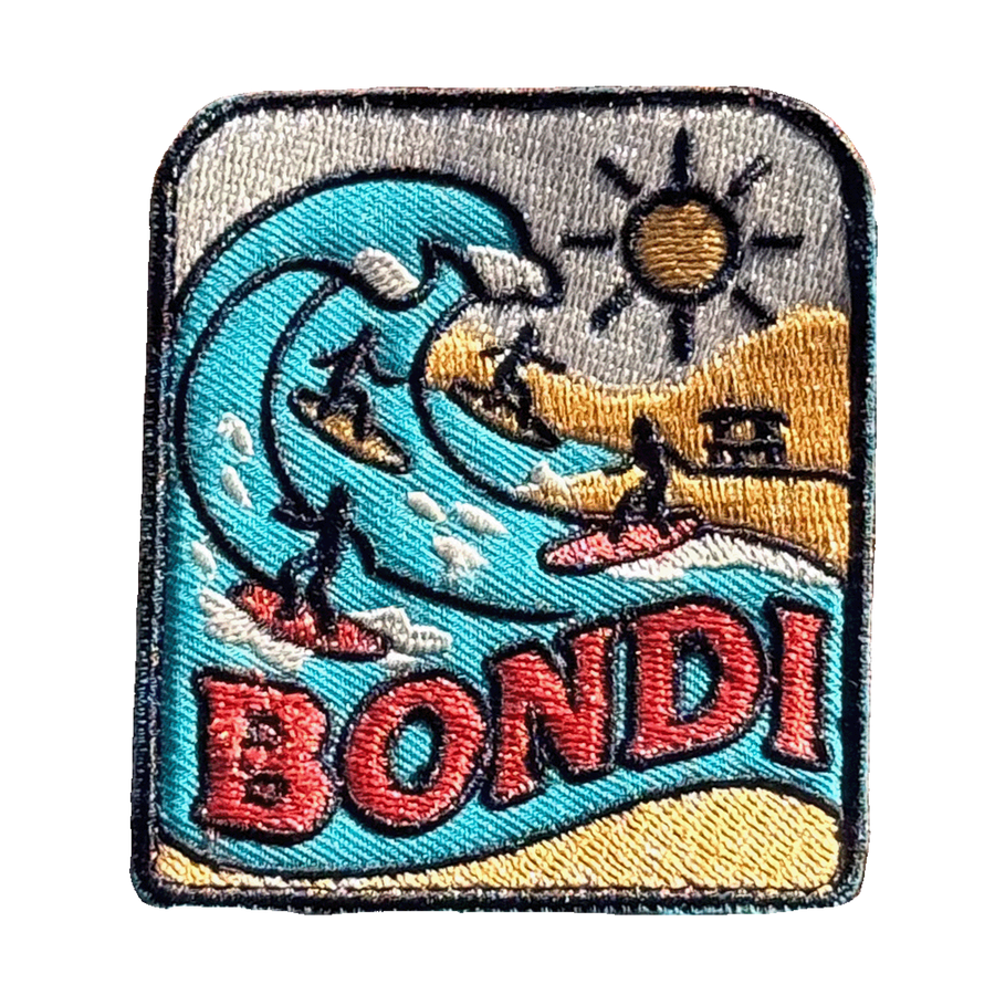 Bondi Beach embroidered travel patch featuring four surfers riding turquoise ocean waves beside a sunny golden beach.