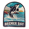 Bremer Bay embroidered travel patch featuring breaching orca splashing in the ocean near a rocky coastline at sunset.