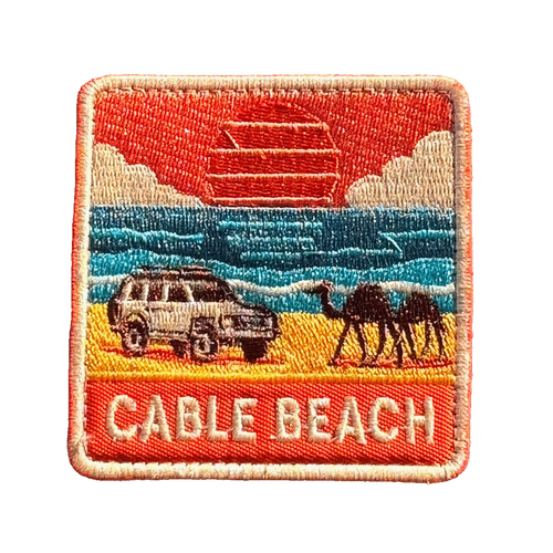 Broome - Cable Beach embroidered travel patch featuring 4WD and two camels on golden sand beside turquoise ocean at sunset.