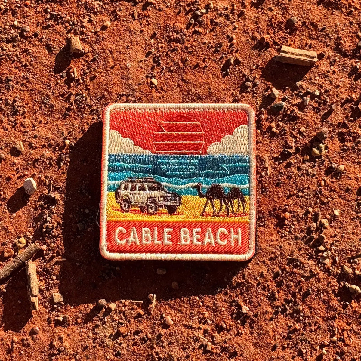 Broome - Cable Beach embroidered travel patch featuring 4WD and two camels on golden sand beside turquoise ocean at sunset.