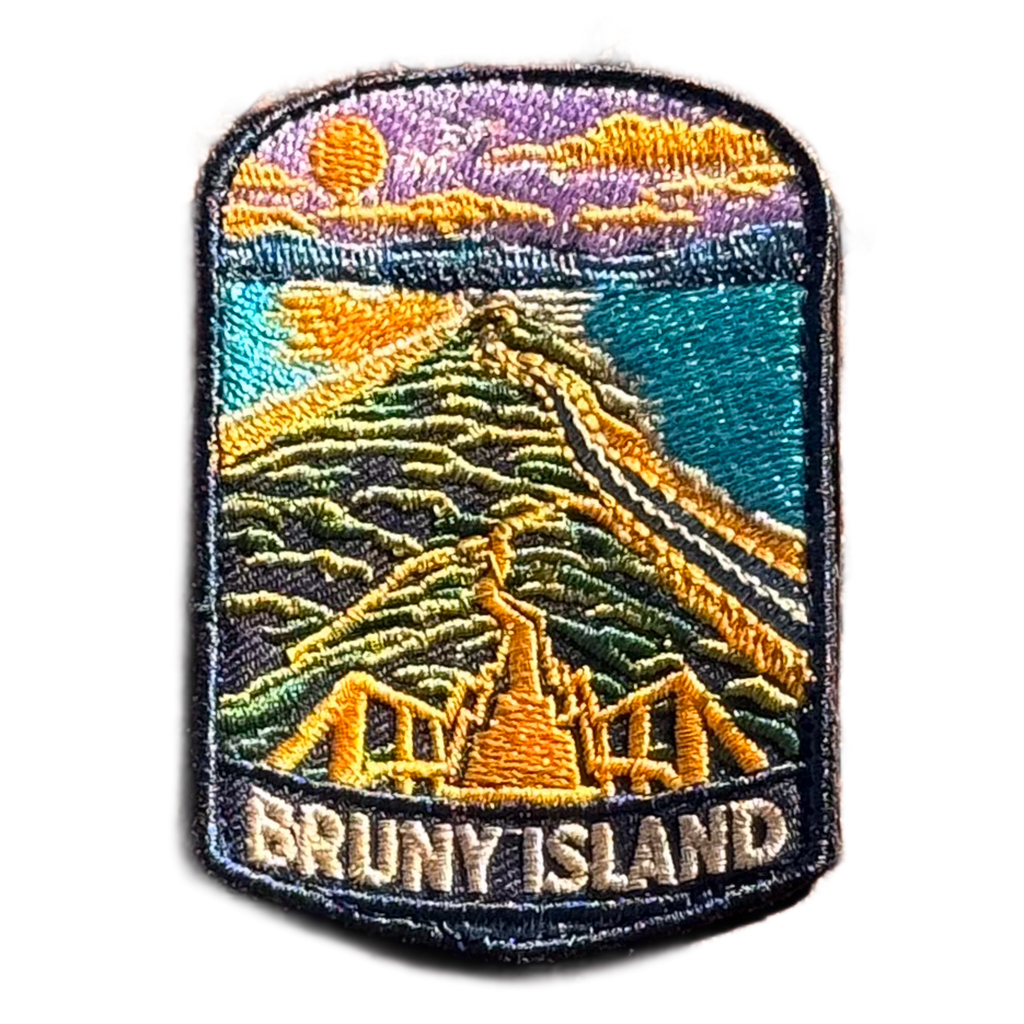 Bruny Island embroidered travel patch with a white lighthouse overlooking a rugged island coast; photographed on a transparent background.