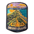 Bruny Island embroidered travel patch with a white lighthouse overlooking a rugged island coast; photographed on a transparent background.