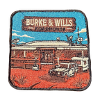 Burke And Wills Roadhouse embroidered travel patch with a remote roadhouse in red outback country; photographed on a transparent background.