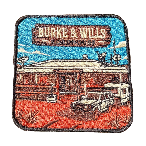 Burke And Wills Roadhouse embroidered travel patch with a remote roadhouse in red outback country; photographed on a transparent background.