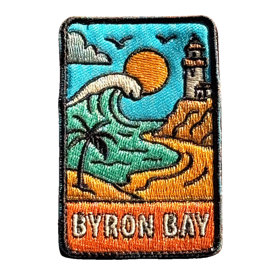 Byron Bay embroidered travel patch with Cape Byron Lighthouse above the coast; photographed on a transparent background.