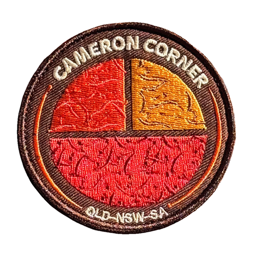 Cameron's Corner embroidered travel patch with a survey marker in the red outback at Cameron Corner; photographed on a transparent background.