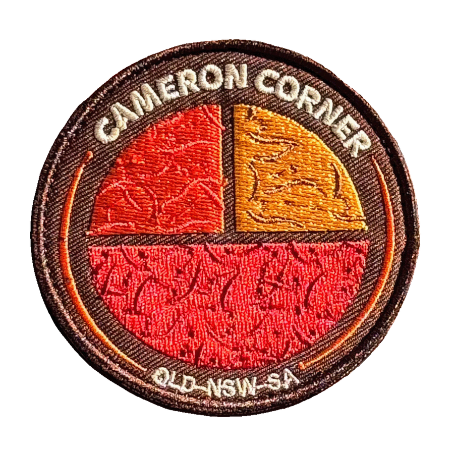 Cameron's Corner embroidered travel patch with a survey marker in the red outback at Cameron Corner; photographed on a transparent background.