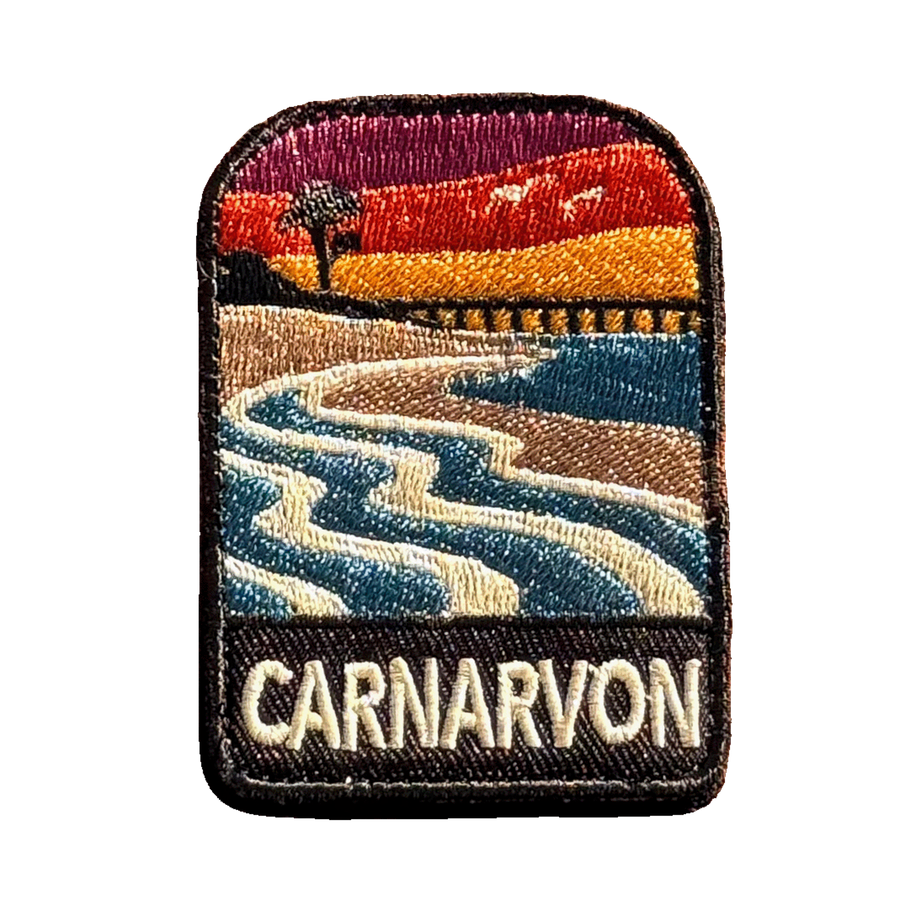 Carnarvon embroidered travel patch with a coastal jetty and palm trees; photographed on a transparent background.