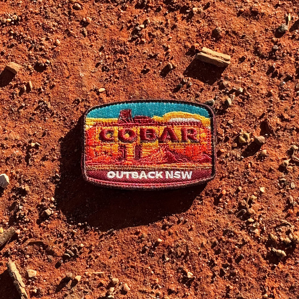 Cobar embroidered travel patch with a mining headframe in a red outback landscape.