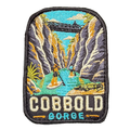 Cobbold Gorge embroidered travel patch with a boat travelling between narrow sandstone gorge walls; photographed on a transparent background.