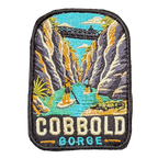 Cobbold Gorge embroidered travel patch with a boat travelling between narrow sandstone gorge walls; photographed on a transparent background.