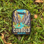 Cobbold Gorge embroidered travel patch with a boat travelling between narrow sandstone gorge walls.