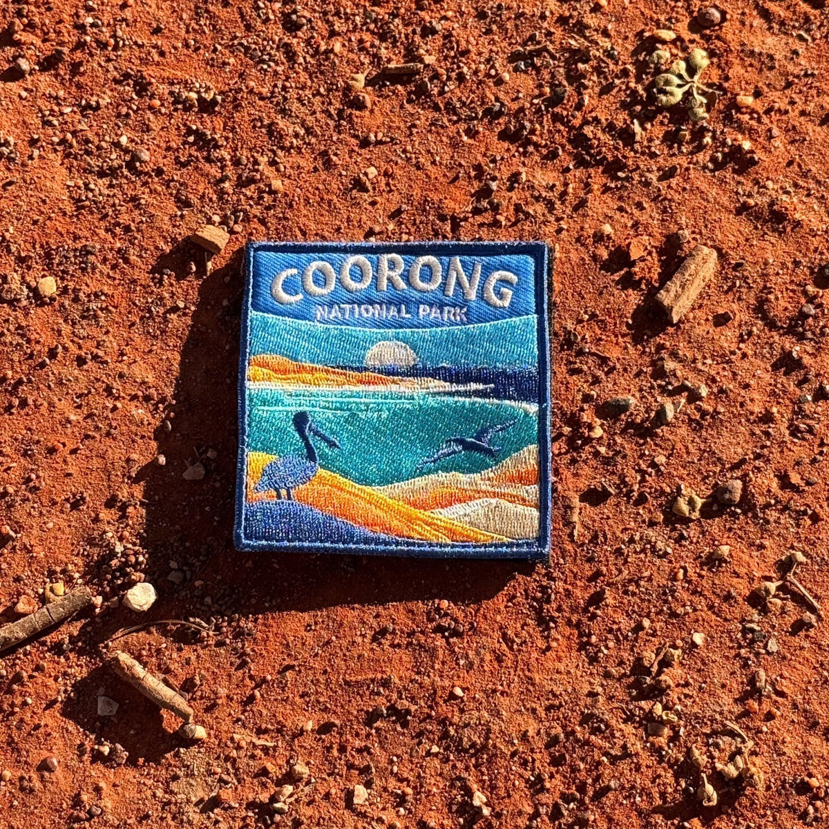 Coorong National Park embroidered travel patch with a pelican on sand dunes and a dolphin in turquoise coastal water.