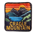 Cradle Mountain embroidered travel patch with Cradle Mountain peaks reflected in a blue lake at sunset; photographed on a transparent background.