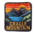 Cradle Mountain embroidered travel patch with Cradle Mountain peaks reflected in a blue lake at sunset; photographed on a transparent background.