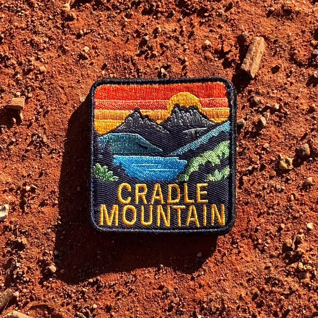 Cradle Mountain embroidered travel patch with Cradle Mountain peaks reflected in a blue lake at sunset.