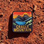 Cradle Mountain embroidered travel patch with Cradle Mountain peaks reflected in a blue lake at sunset.