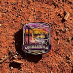 Cunnamulla - Charlotte Plains embroidered travel patch with a person relaxing in an outdoor bath at Charlotte Plains beneath a sunset sky.