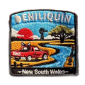Deniliquin embroidered travel patch with a red ute, guitar, windmill and winding river beneath an orange sunset; photographed on a transparent background.
