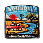 Deniliquin embroidered travel patch with a red ute, guitar, windmill and winding river beneath an orange sunset; photographed on a transparent background.