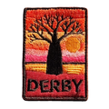 Derby embroidered travel patch with a jetty extending across tidal flats at sunset; photographed on a transparent background.