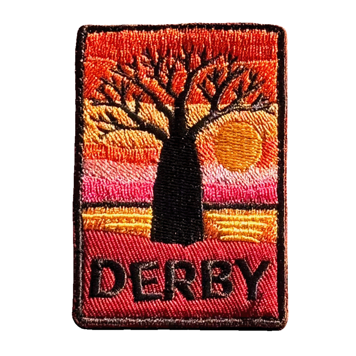 Derby embroidered travel patch with a jetty extending across tidal flats at sunset; photographed on a transparent background.