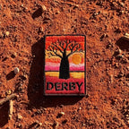 Derby embroidered travel patch with a jetty extending across tidal flats at sunset.