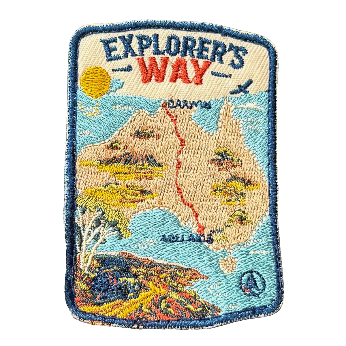 Explorers Way embroidered travel patch with an outback road through red desert country; photographed on a transparent background.