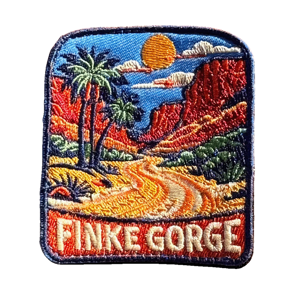 Finke Gorge embroidered travel patch with red gorge walls and desert vegetation; photographed on a transparent background.
