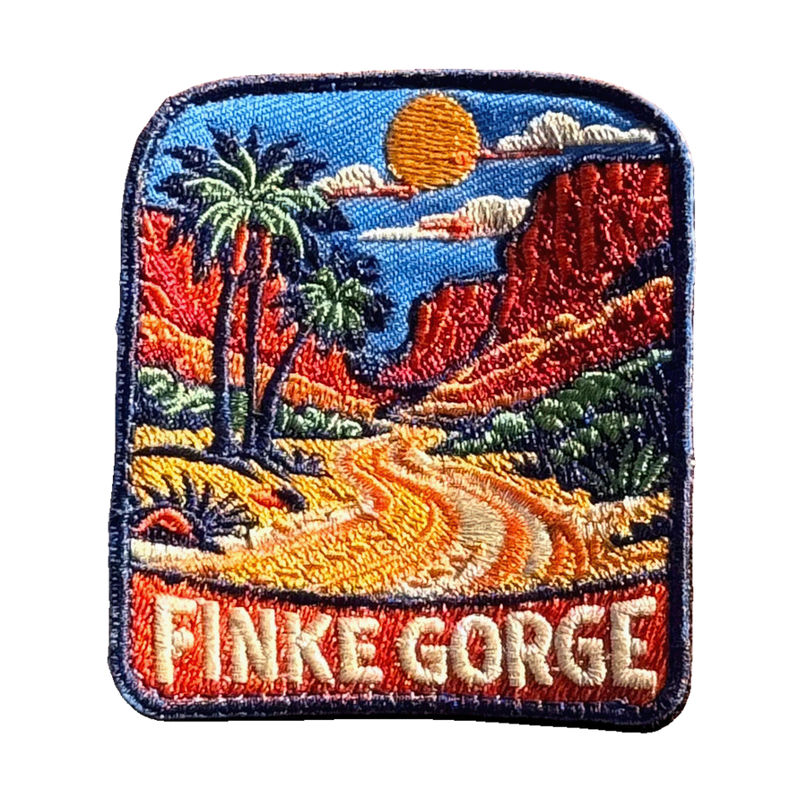 Finke Gorge embroidered travel patch with red gorge walls and desert vegetation; photographed on a transparent background.