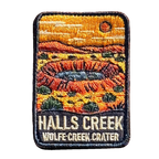 Halls Creek - Wolfe Creek Crater embroidered travel patch with the circular Wolfe Creek Crater in a red desert landscape; photographed on a transparent background.