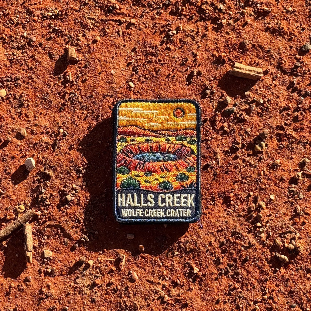 Halls Creek - Wolfe Creek Crater embroidered travel patch with the circular Wolfe Creek Crater in a red desert landscape.