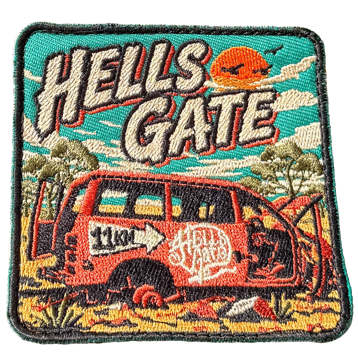 Hells Gate embroidered travel patch with a rusty outback vehicle beside an 11 km sign at Hells Gate; photographed on a transparent background.