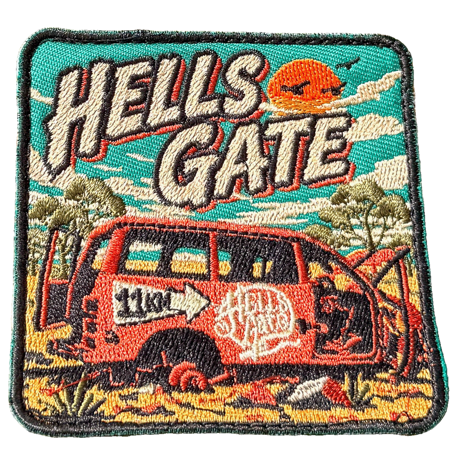 Hells Gate embroidered travel patch with a rusty outback vehicle beside an 11 km sign at Hells Gate; photographed on a transparent background.