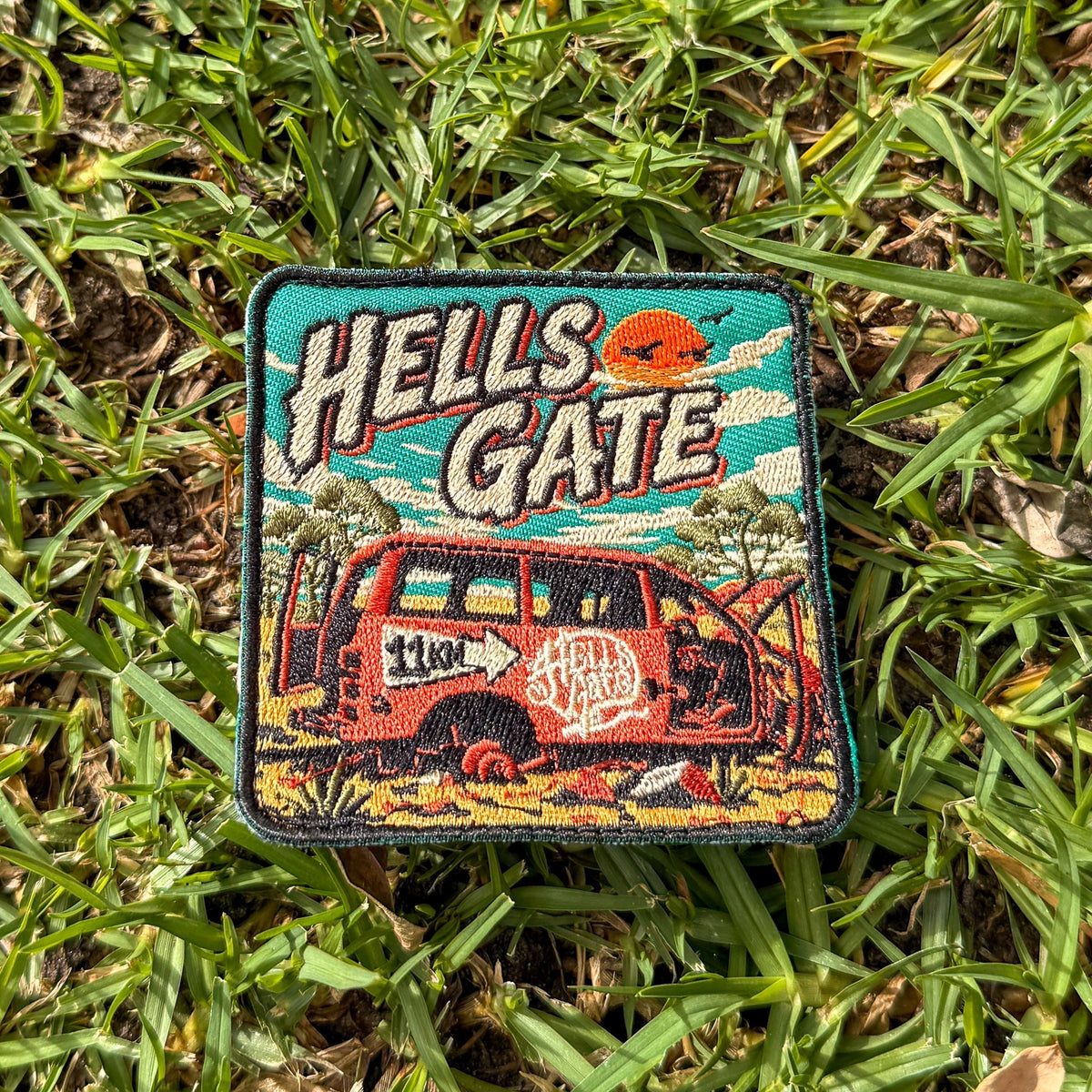Hells Gate embroidered travel patch with a rusty outback vehicle beside an 11 km sign at Hells Gate.