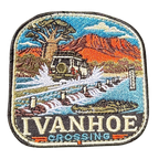 Ivanhoe Crossing embroidered travel patch with a four-wheel drive splashing across a flooded causeway with a crocodile in the water; photographed on a transparent background.